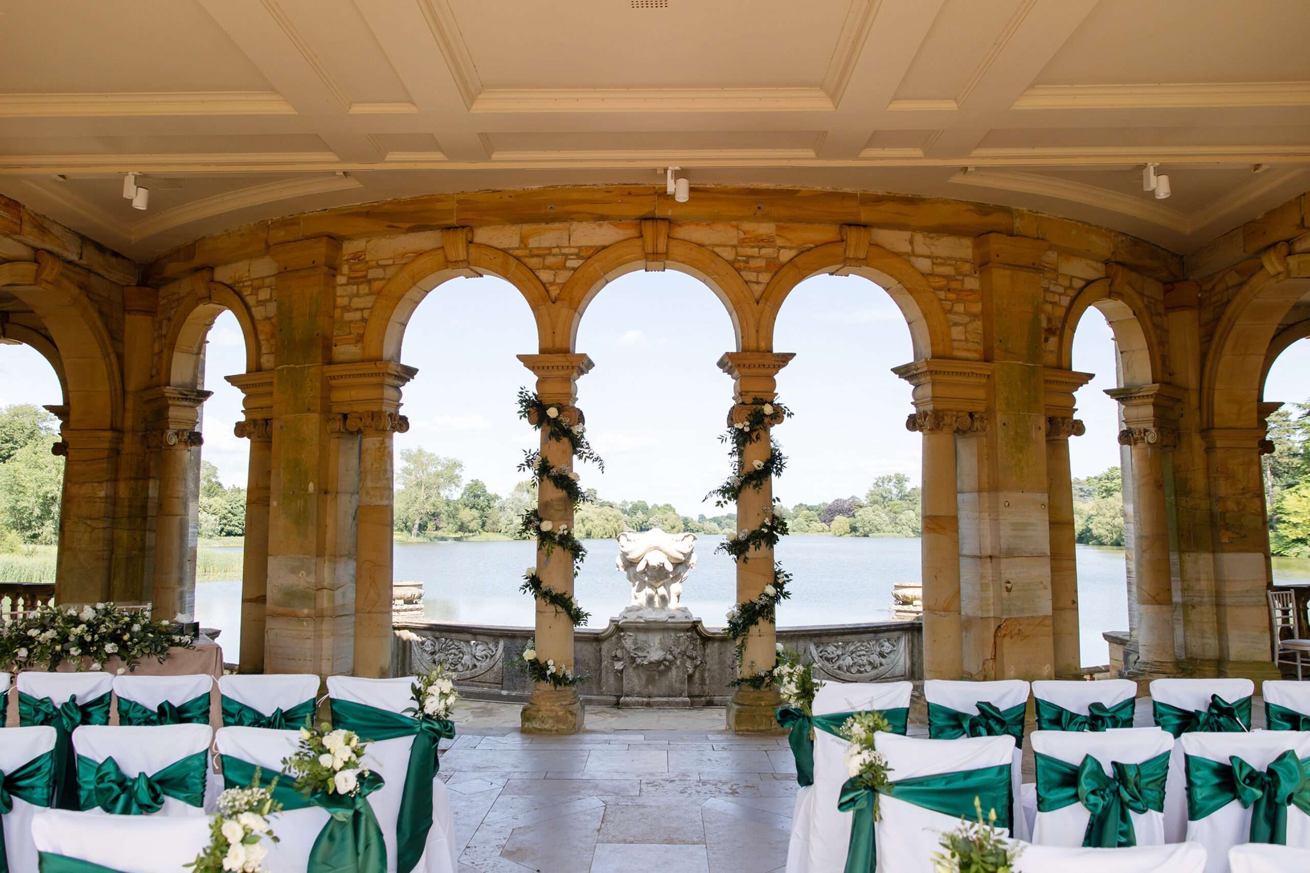The Loggia in the Italian Garden dressed for a ceremony, stone columns and chairs with green sashes above the lake, Hever Castle, Hever, England