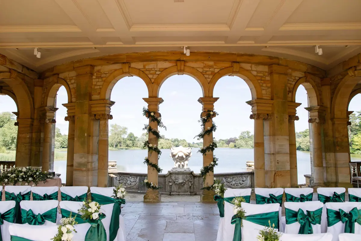 The Loggia in the Italian Garden dressed for a ceremony, stone columns and chairs with green sashes above the lake, Hever Castle, Hever, England