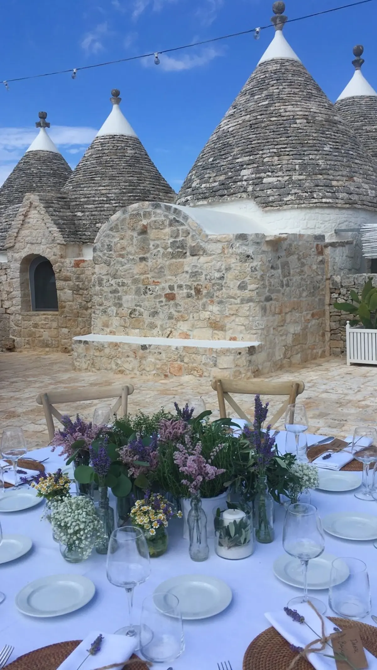 A table laid in white and lavender in front of the trulli in Puglia