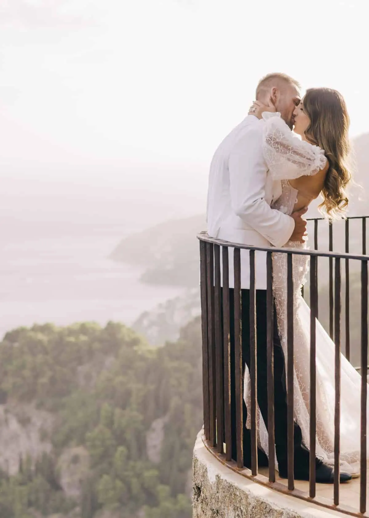 The first kiss on a cliffside balcony, sea and coastline behind, Amalfi Coast