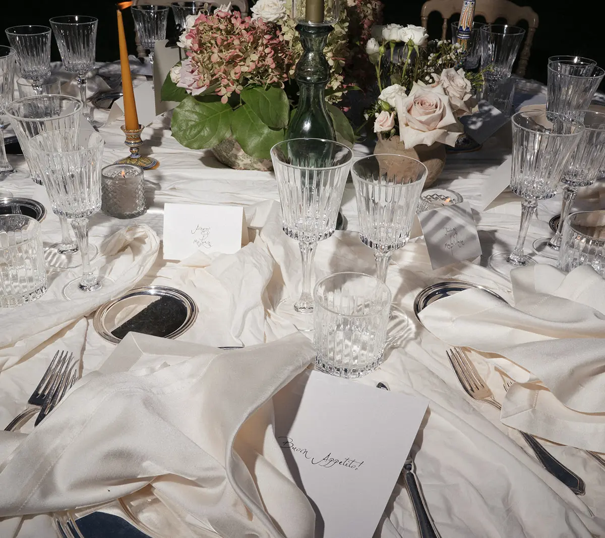A round wedding table close up: cut crystal, silk cloth and a hydrangea centrepiece