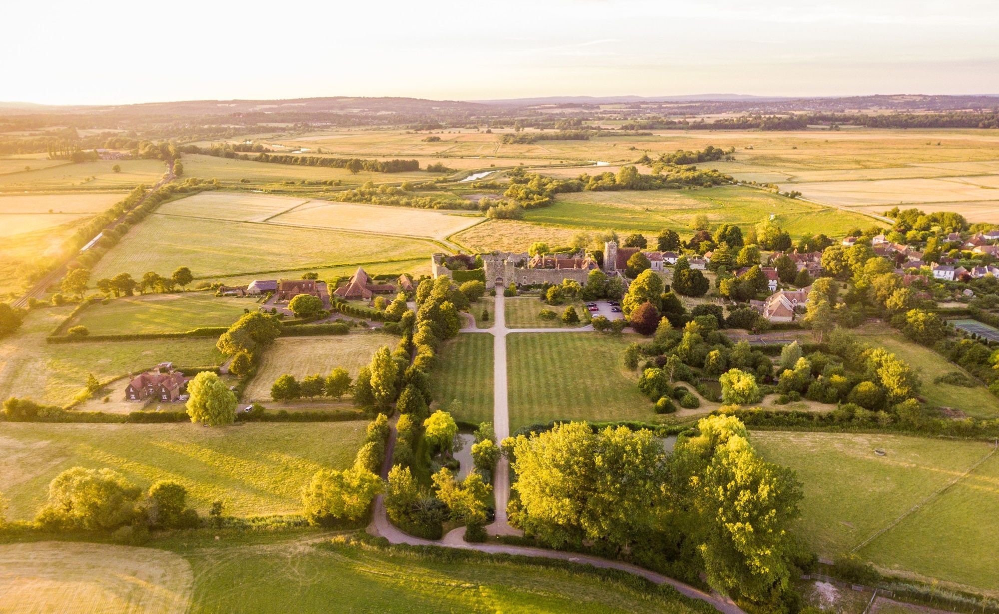An aerial view of the castle and its walled gardens set in the rolling South Downs, lit by late afternoon sun, Amberley Castle, Amberley, England