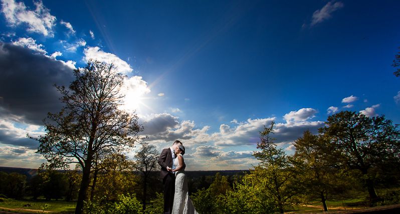 A bride and groom kissing beneath a bright blue sky, Pembroke Lodge