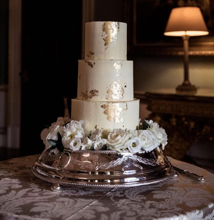 A gold-leaf wedding cake, finished with a base of white roses