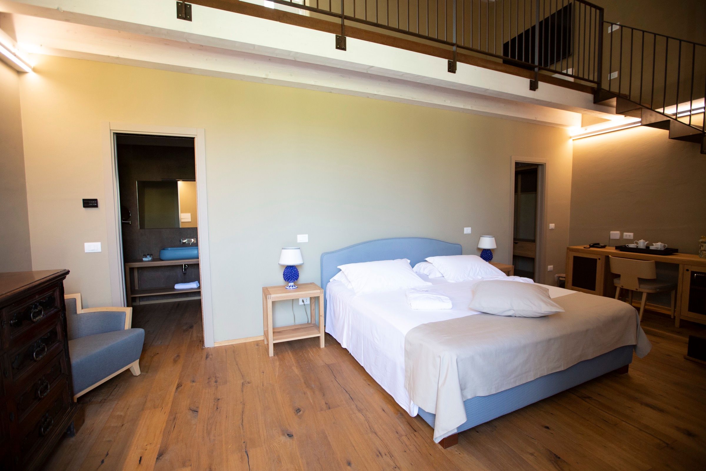 A room finished in soft blue, twin bedside lamps lit