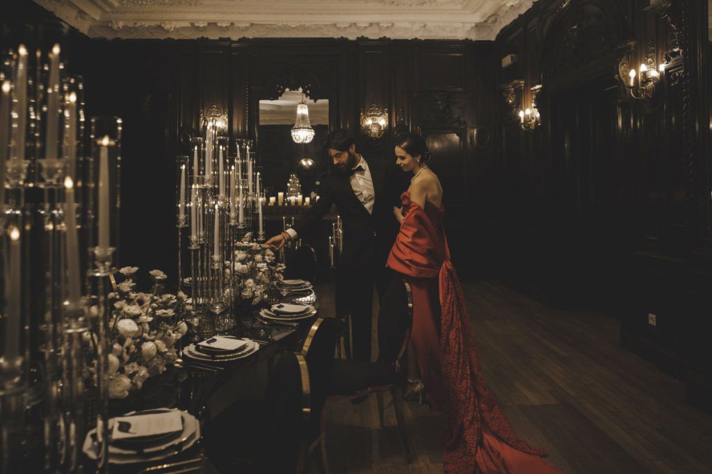 A candlelit reception table in white rose, set within a darkened, panelled room