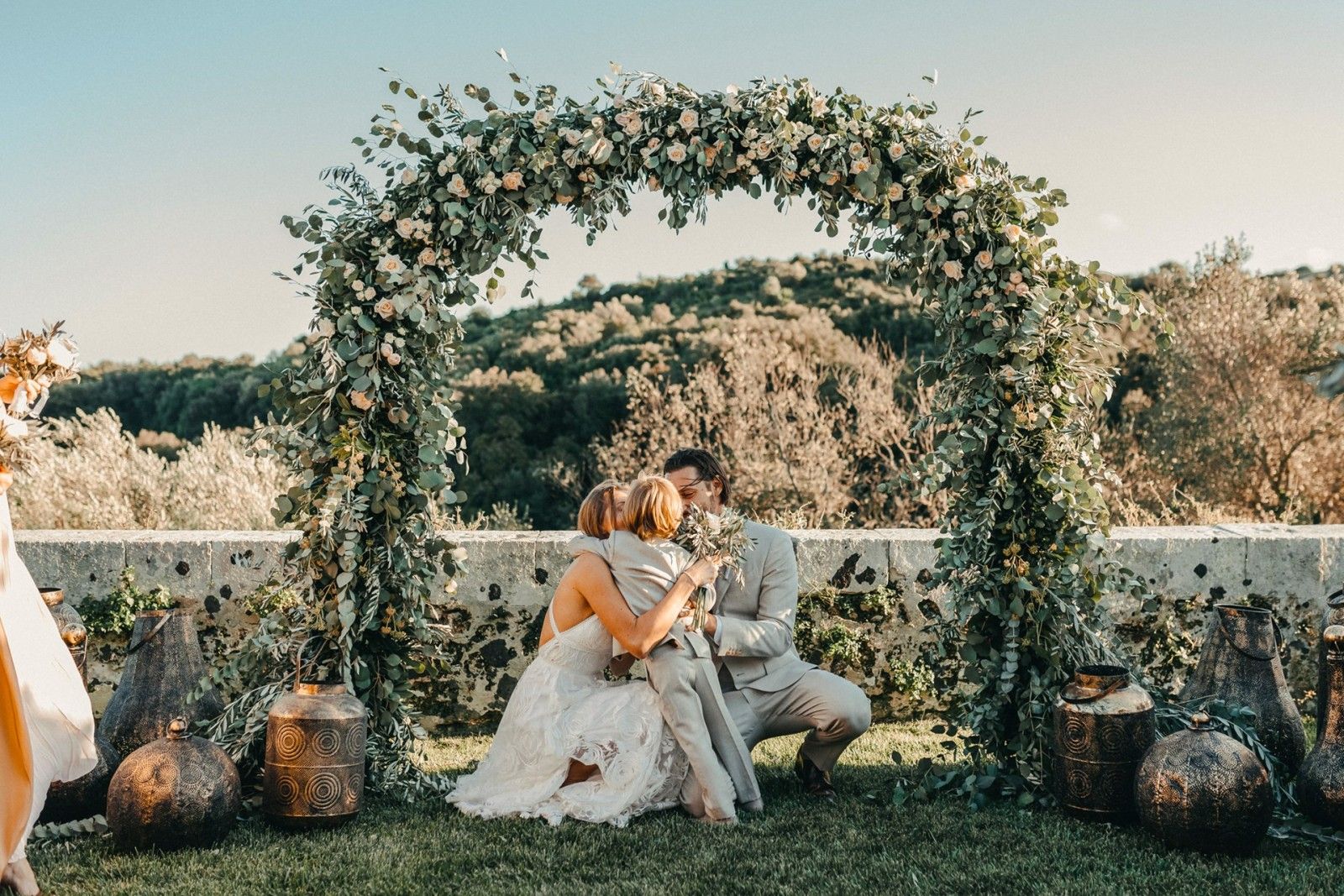 Seated beneath a floral arch on the lawn