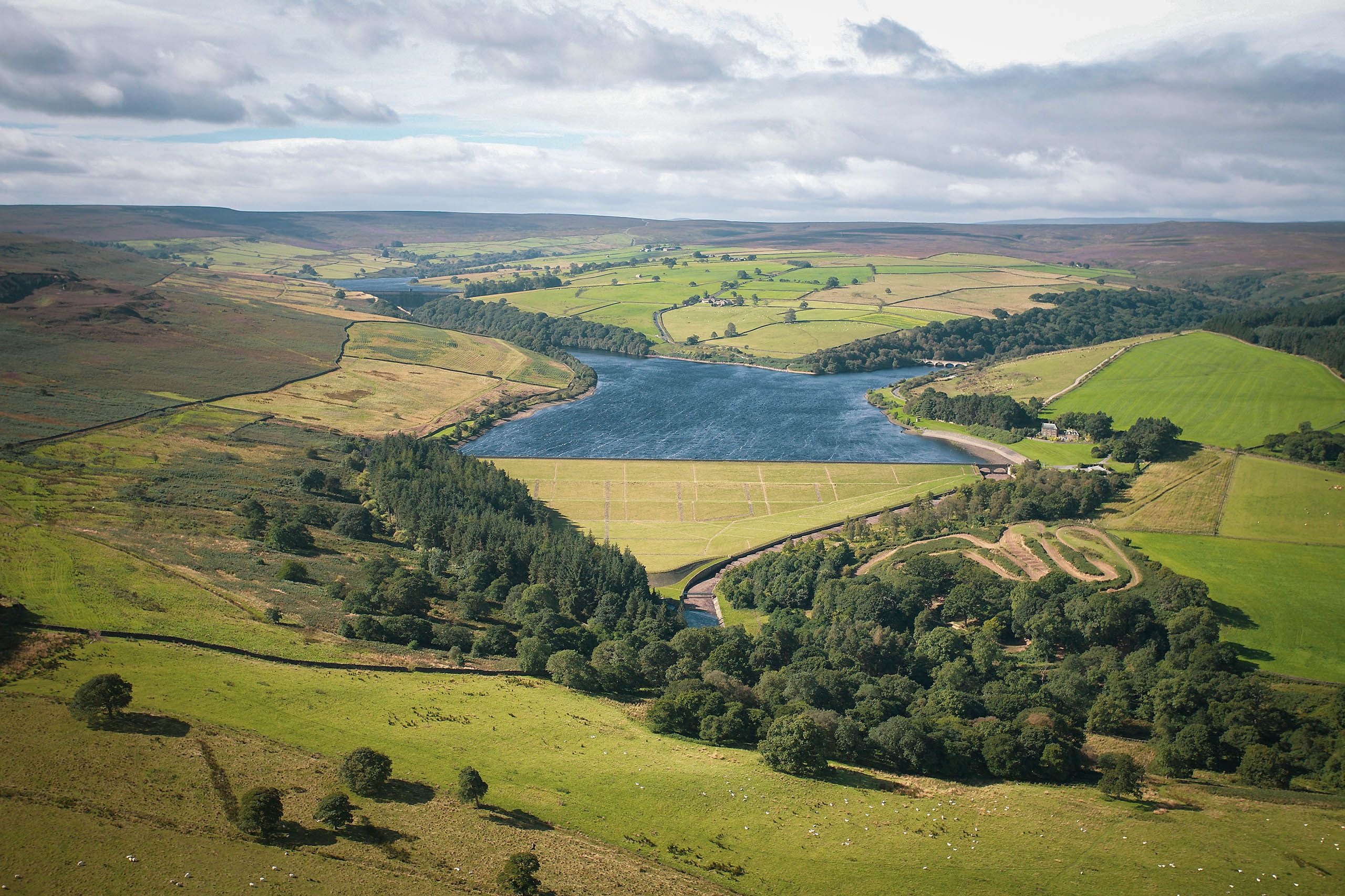 An aerial view of the estate reservoir set among the fields and moorland of the Dales