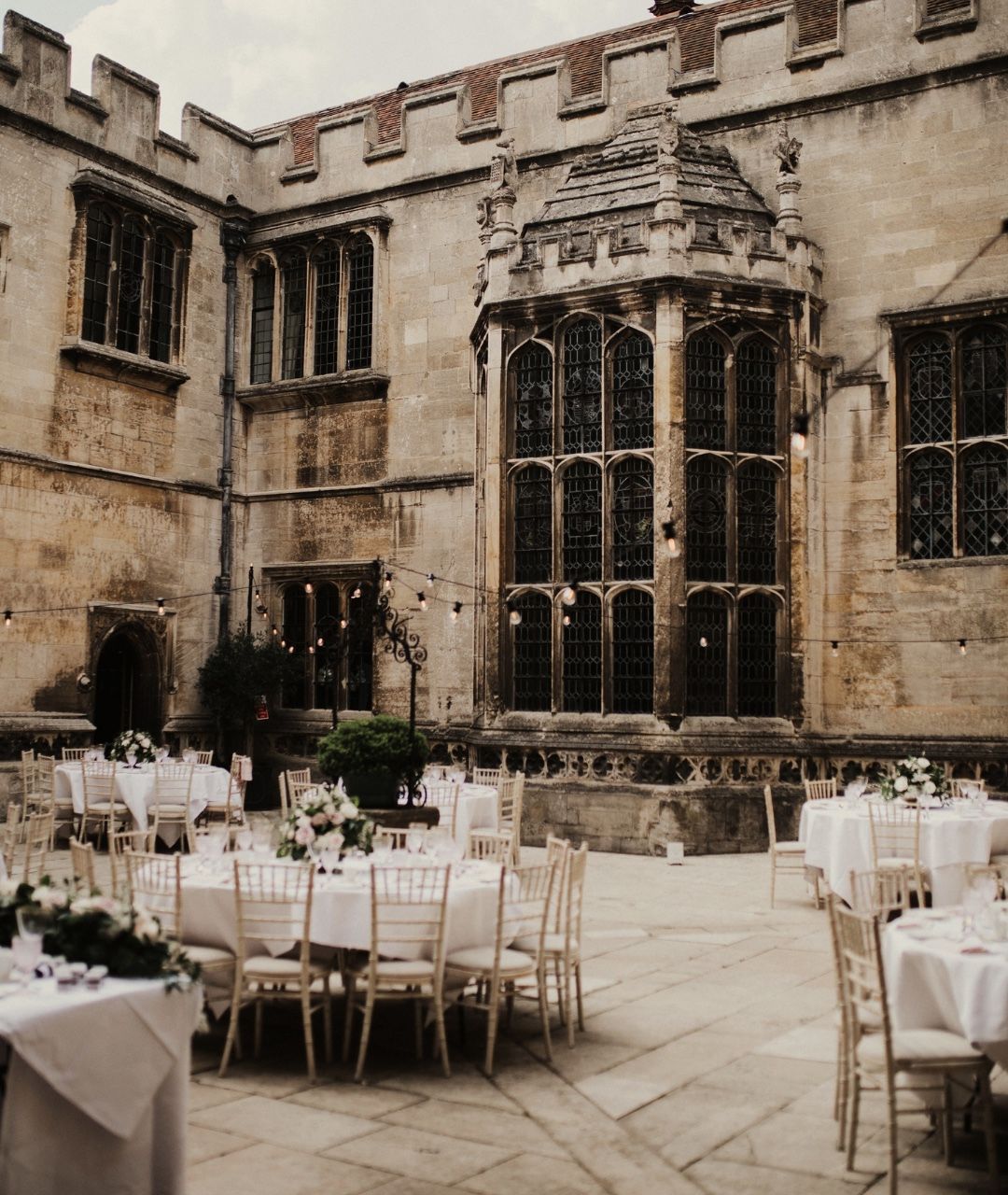 The Italian-style courtyard set with round tables for dining within the Tudor stone walls