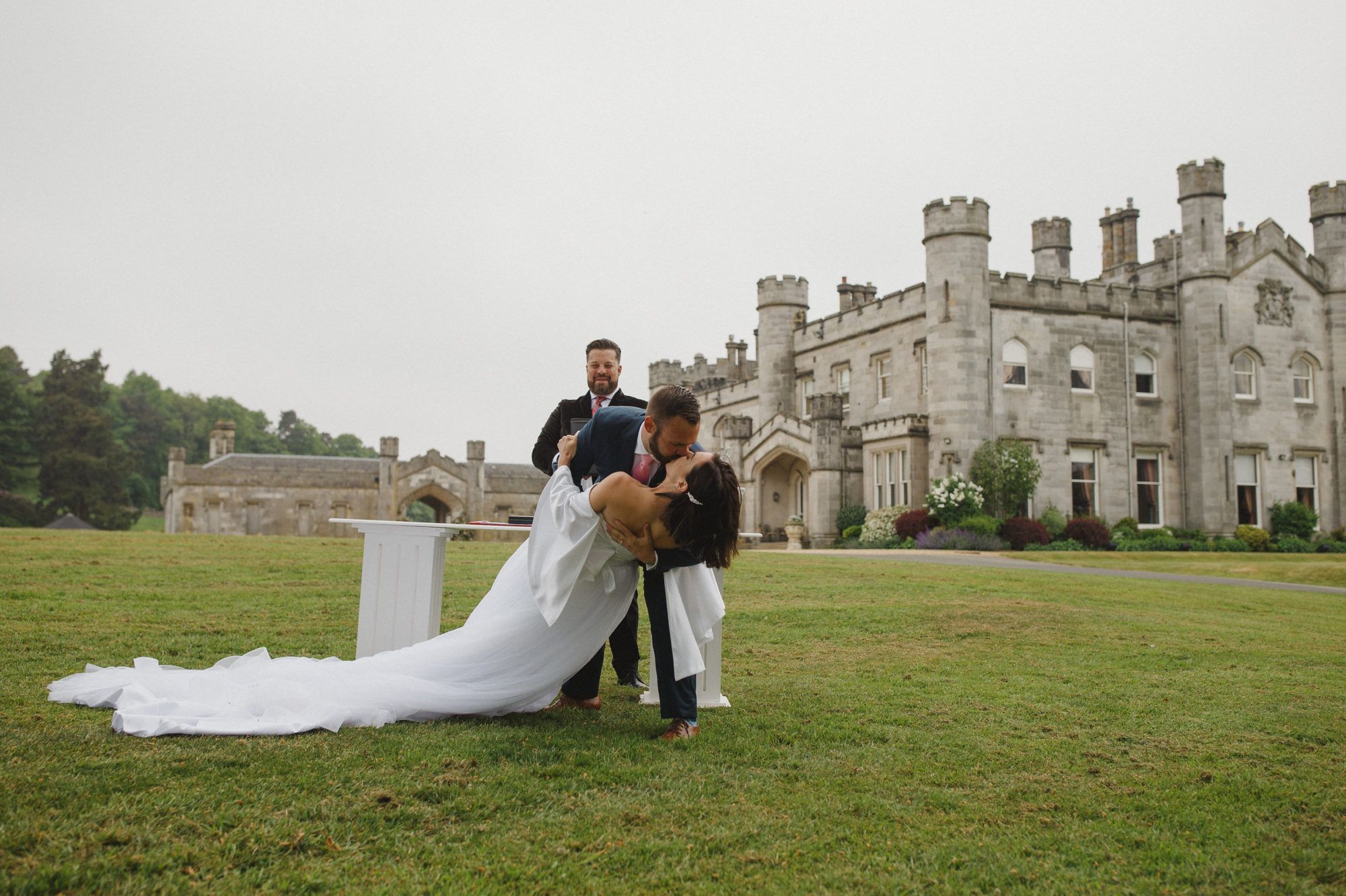 A groom lifting his bride on the lawn before the castle