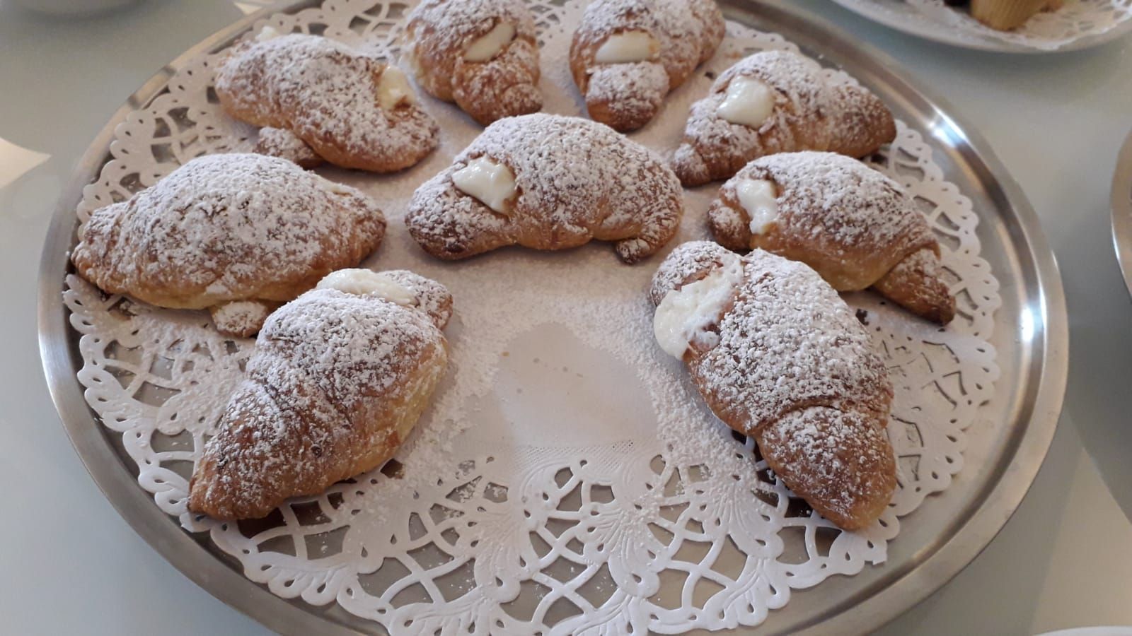Fresh cornetti, dusted with sugar, on a silver tray