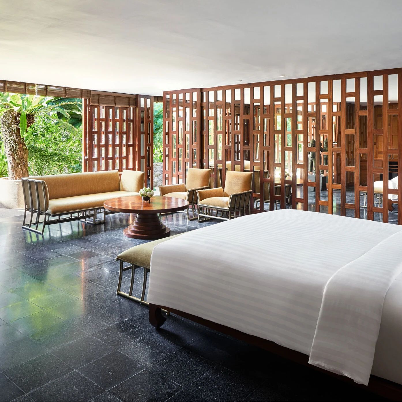 A villa living area at Amanpuri, timber lattice screens opening onto the garden