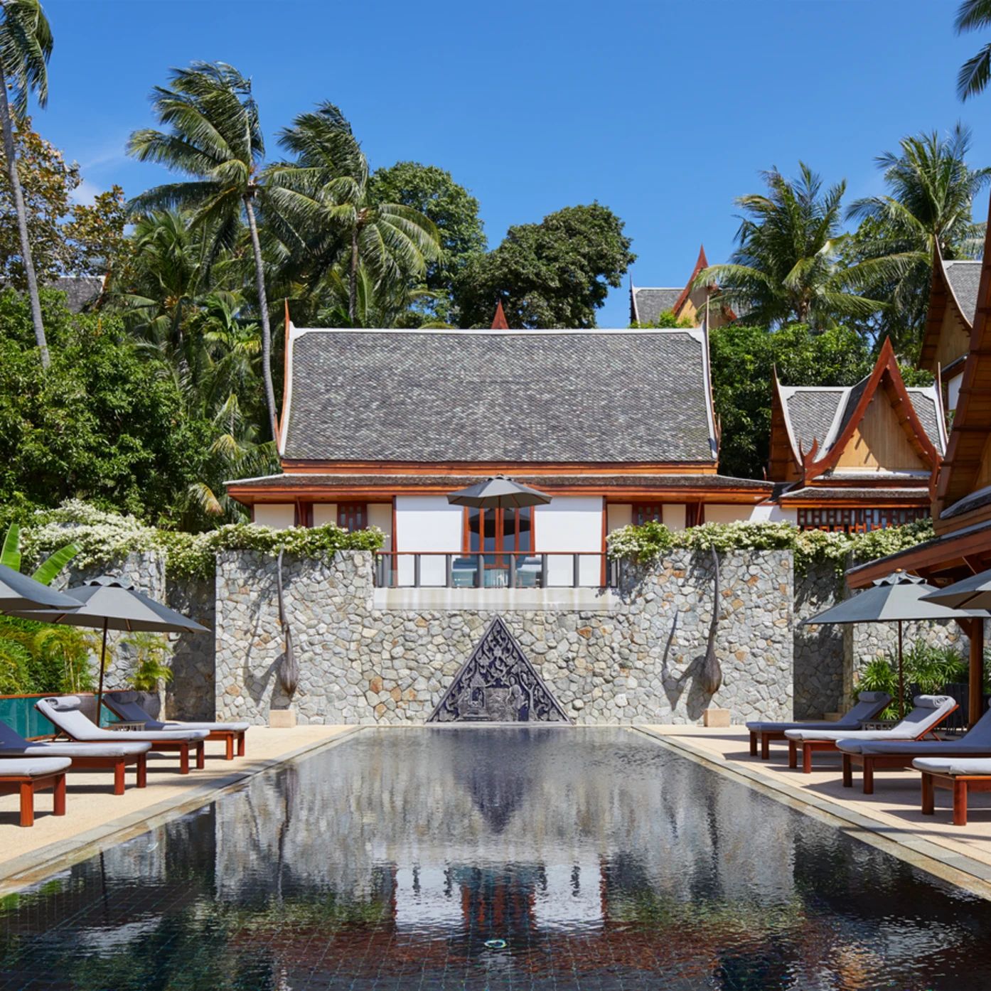 A villa pool at Amanpuri framed by palms and a Thai-roofed pavilion