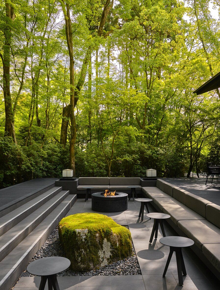 A forest garden terrace at Aman Kyoto, with a fire pit and moss-covered stone